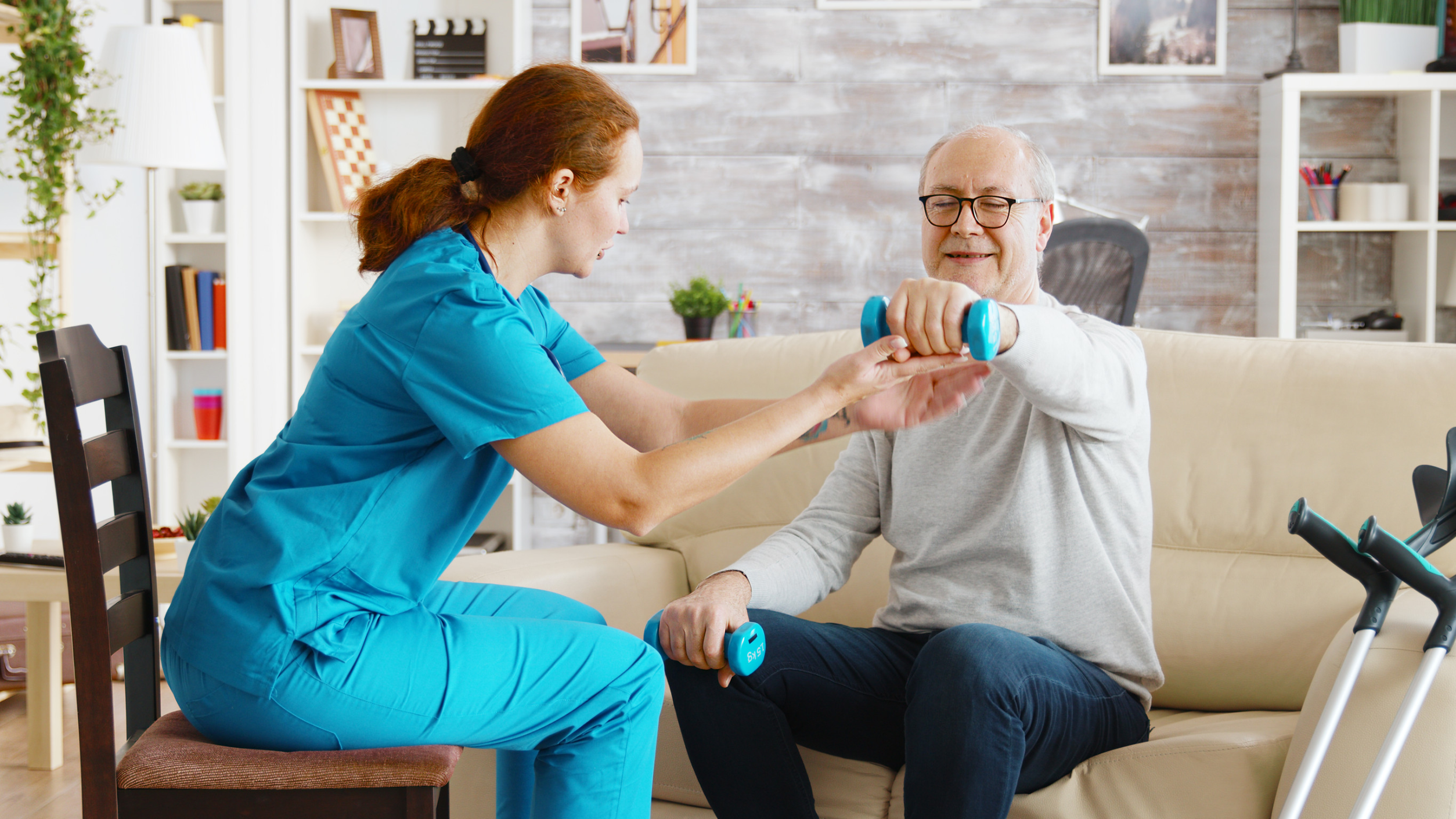 Female nurse helps an old man to make his morning exercises in bright and cozy retirement home Young Latin women doing yoga and pilates exercises at home - Sport wellness lifestyle concept<br />