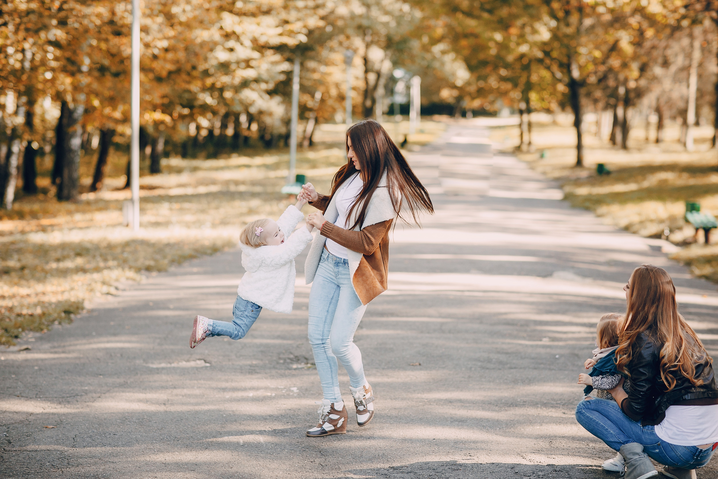 great trendy young mothers walking in the park with his daughters in beautiful clothing great trendy young mothers walking in the park with his daughters in beautiful clothing