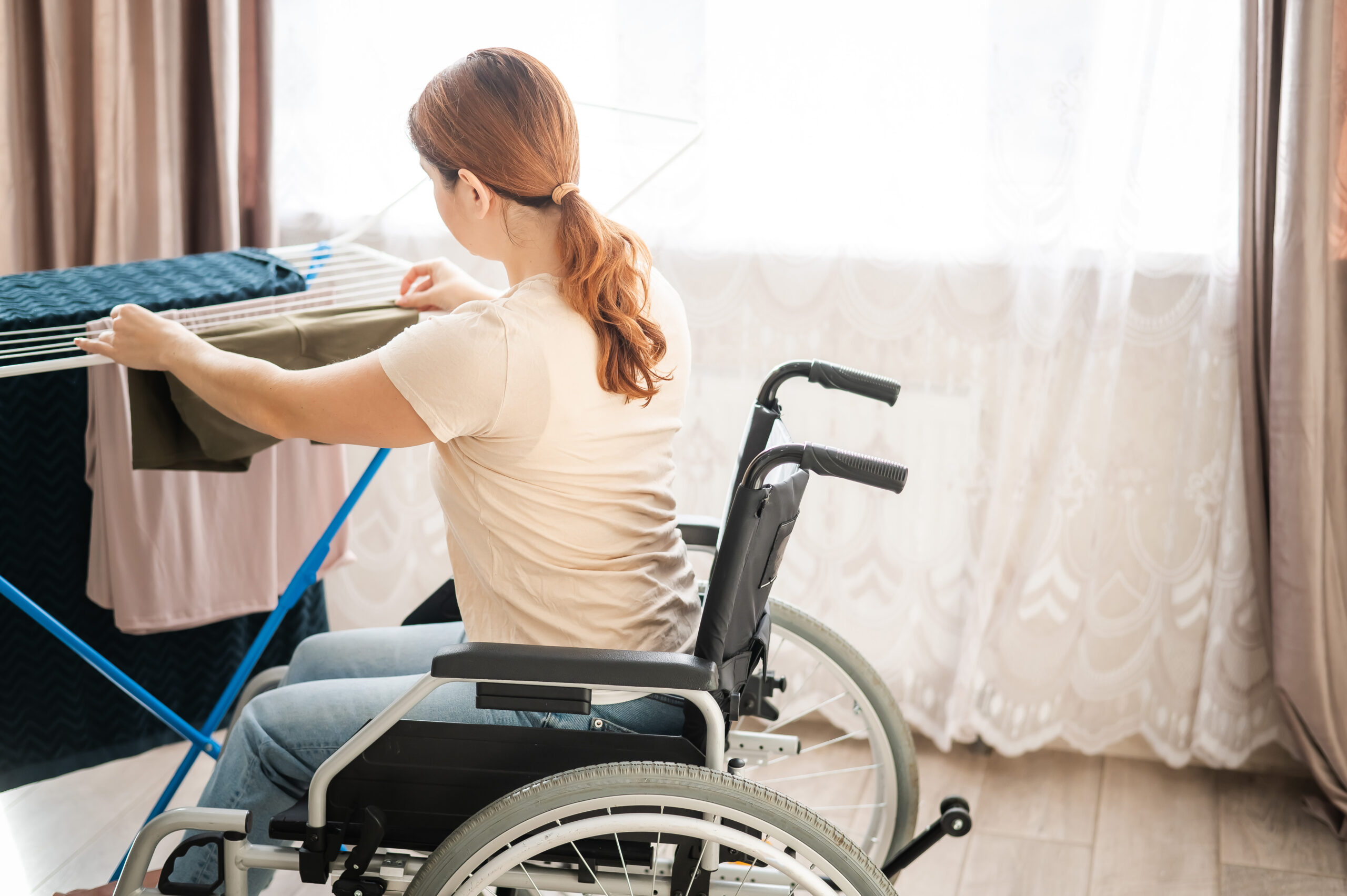 Caucasian woman in a wheelchair hangs wet laundry on a dryer. Beautiful nature landscapes in Turkey mountains. Lycian way is famous among hikers.
